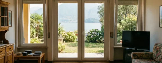 Soggiorno con vecchi serramenti ingombranti e arredo classico prima della ristrutturazione.