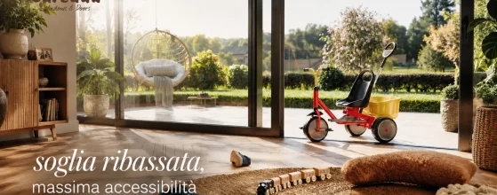 Grande vetrata scorrevole Reynaers ConceptPatio 130 a soglia ribassata che collega il soggiorno con pavimento in legno a un patio esterno con giardino. Nel soggiorno ci sono giocattoli per bambini e sul patio un triciclo.
